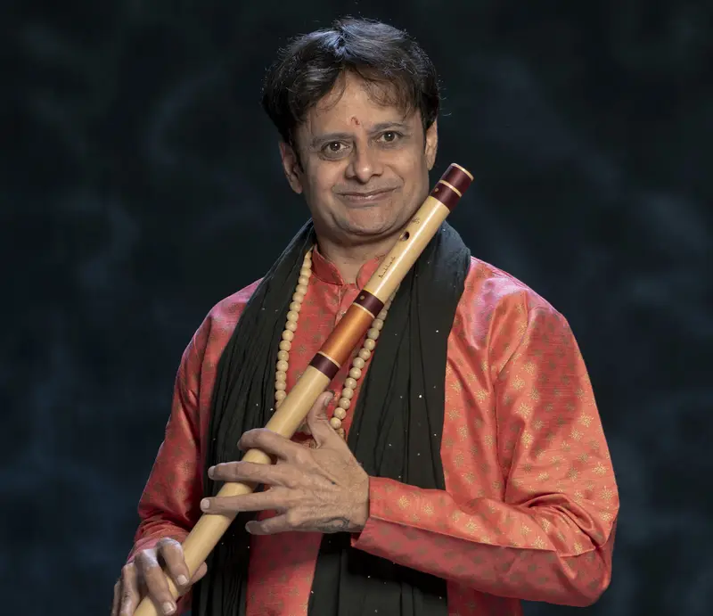 Portrait of Prakash Hegde with a bansuri in a coral kurta