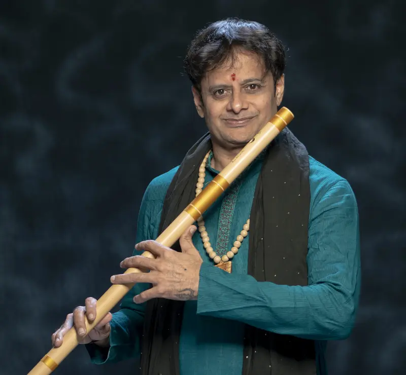 Prakash Hegde holding a bansuri in a teal kurta